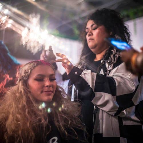 A stylist at a cosmetology school uses a lighter for hair treatment on a client.