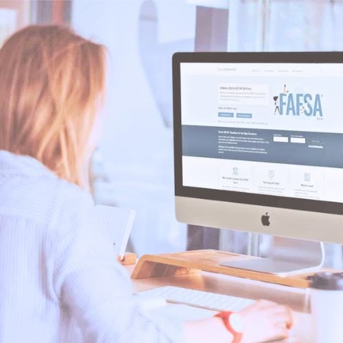 Woman working on a computer at a hair salon with the FAFSA website open.