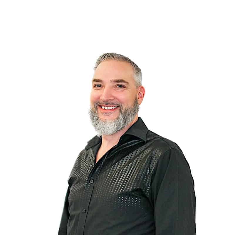 Smiling man with a beard wearing a black shirt against a white background, fresh from the salon.