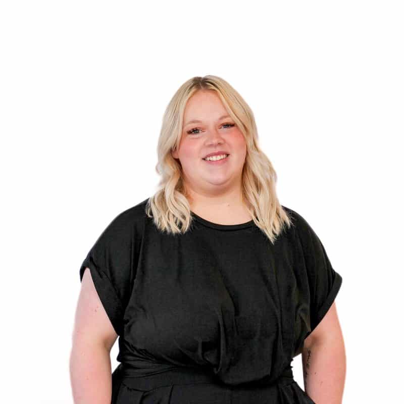 Woman in black attire, radiating beauty, smiling against a white background.