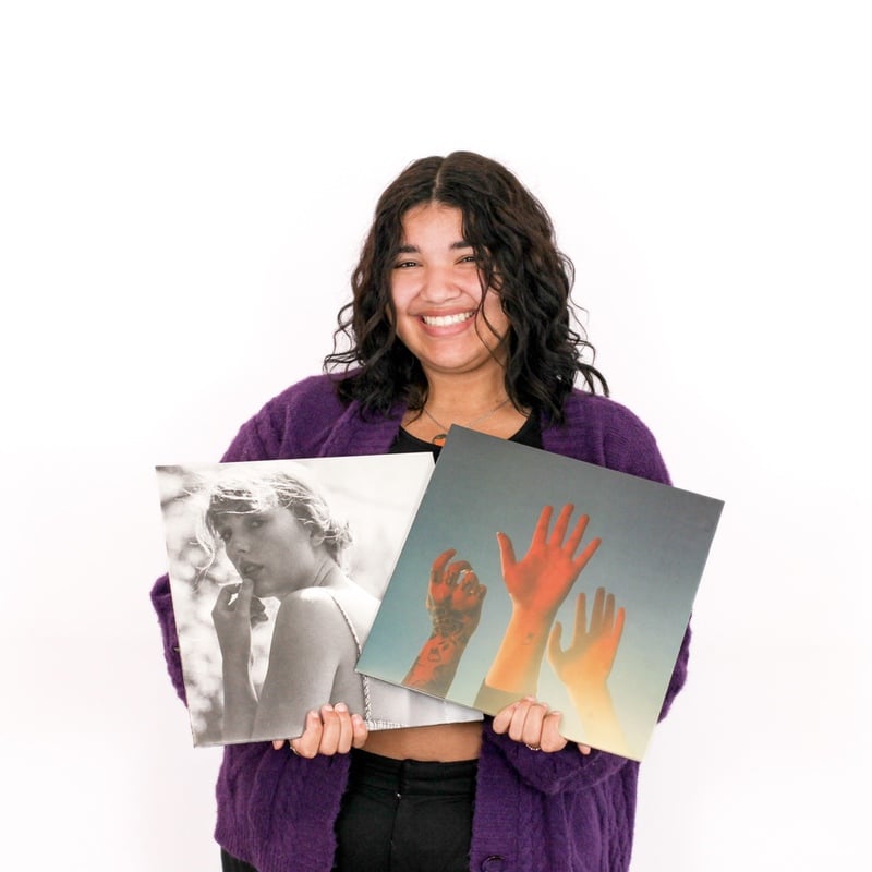 A cheerful person holding vinyl record covers at a stylish hair salon.