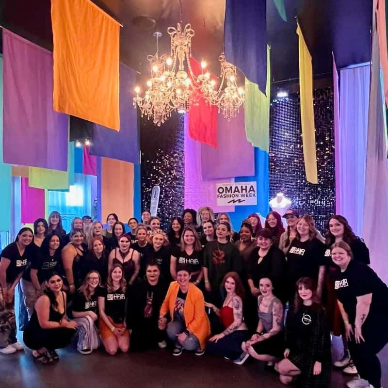 Group of people from a cosmetology school posing for a photo at the Omaha Fashion Week event.