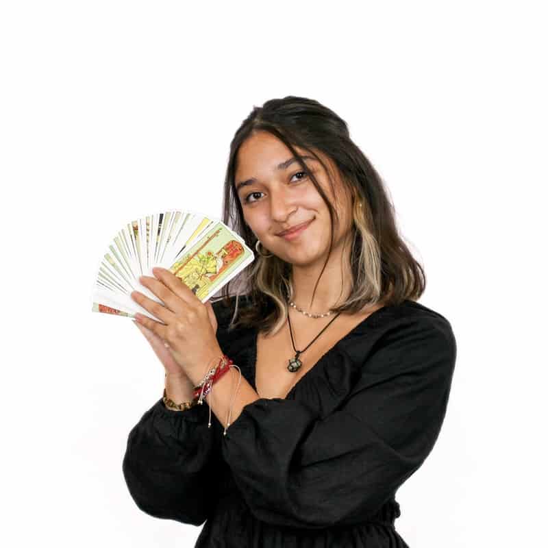 A woman holding a fan of cards and smiling at the camera in an Omaha hair salon.