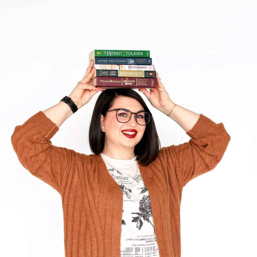 A woman balancing a stack of books on her head at beauty school.